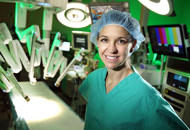 Dr. Stewart stands in front of surgical robot